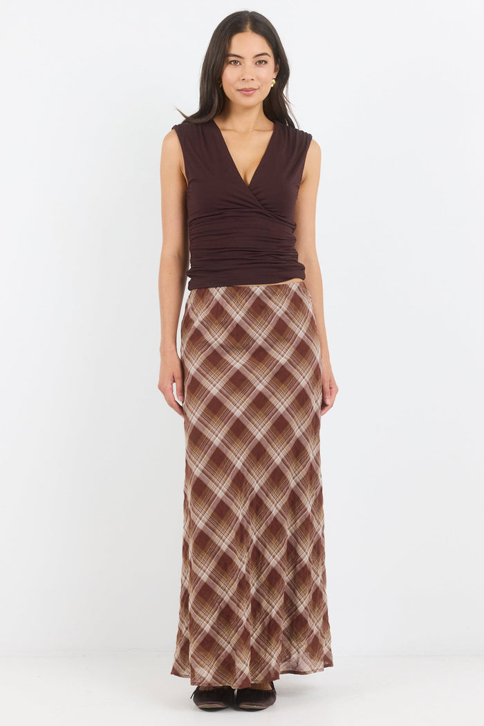 Woman wearing a patterned skirt and brown top on a white background