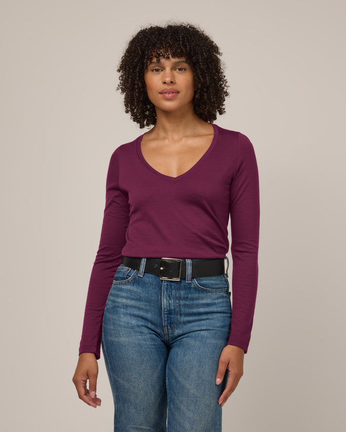 Model wearing Brenton V-Neck Tee in Plum, a warm purple-red color. Brenton V-Neck Tee is a merino wool long sleeve, v-neck, regular fit tee available in sizes XS-3X.