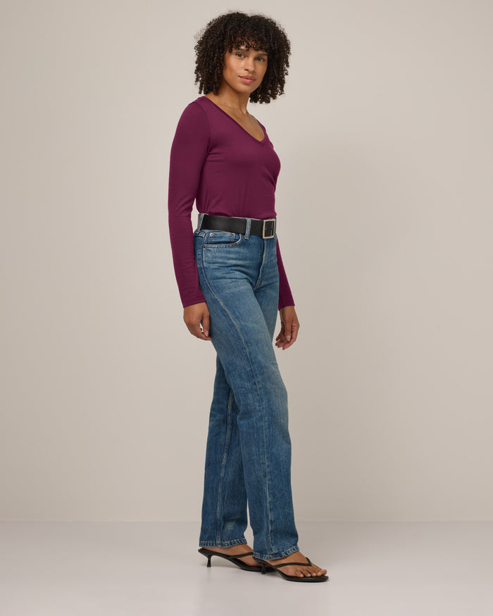 Model wearing Brenton V-Neck Tee in Plum, a warm purple-red color. Brenton V-Neck Tee is a merino wool long sleeve, v-neck, regular fit tee available in sizes XS-3X.