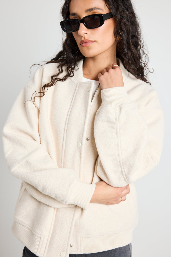 model wears a white bomber jacket with grey pants