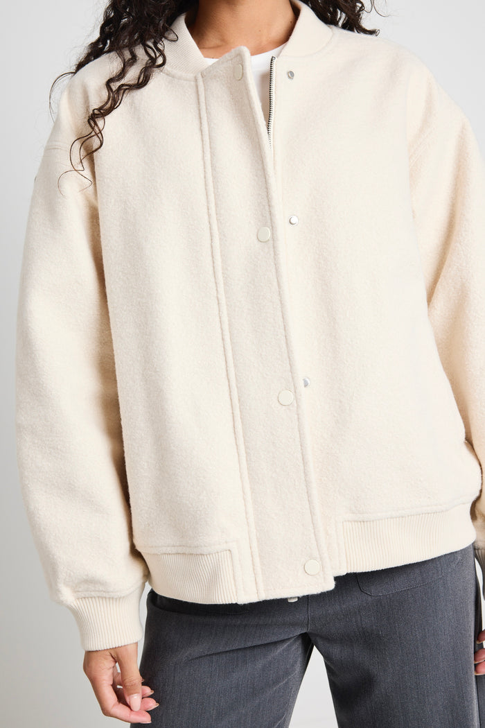 model wears a white bomber jacket with grey pants