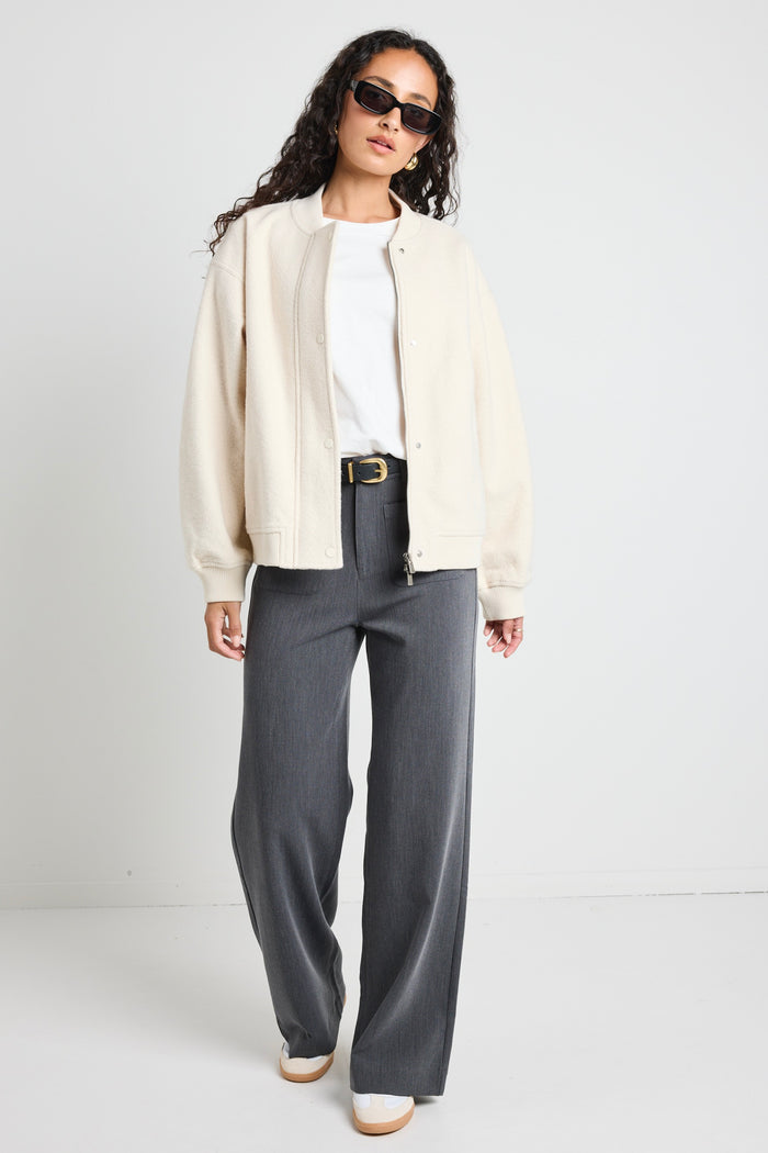 model wears a white bomber jacket with grey pants