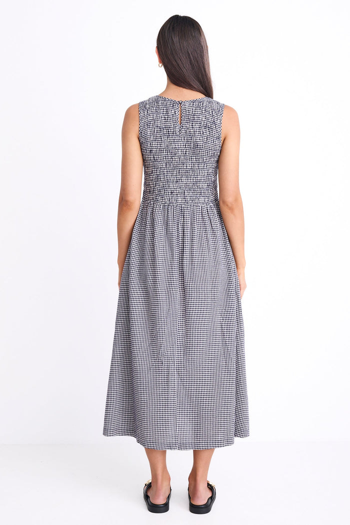 Woman wearing a sleeveless, long, checkered dress on a white background
