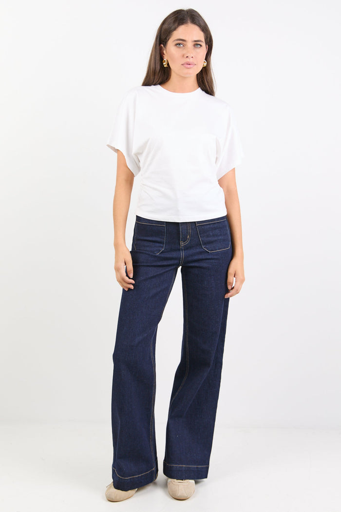 Woman wearing a white top and blue jeans on a white background