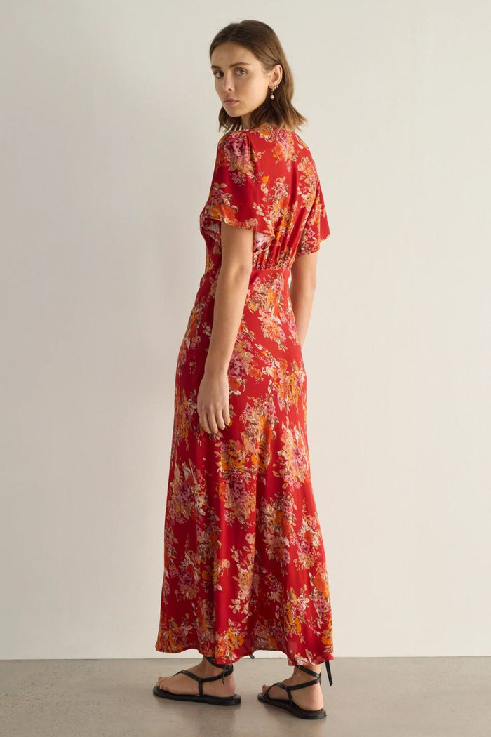Woman wearing a red floral dress on a plain background