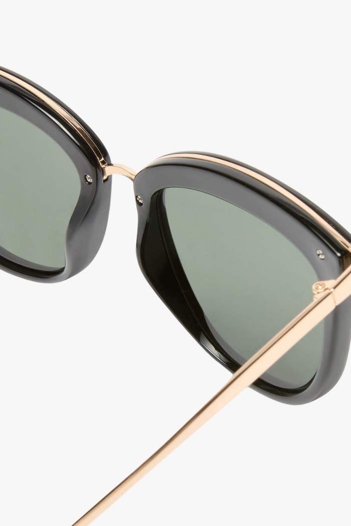 cat-eye sunglasses featuring a sleek black frame paired with khaki-tinted lenses. A slim gold-tone bridge and matching gold arm accents elevate the look with a modern, minimalist touch.