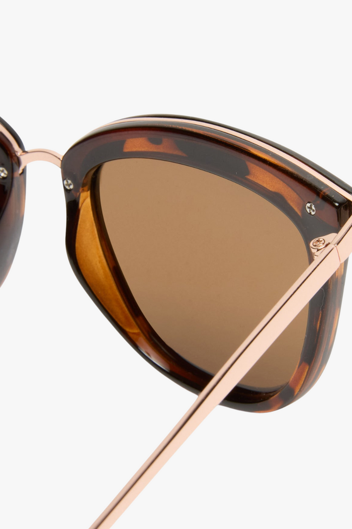 cat-eye sunglasses in a tortoiseshell frame with warm brown lenses. A slim gold-tone bridge and matching gold arms add a polished touch to the bold silhouette.