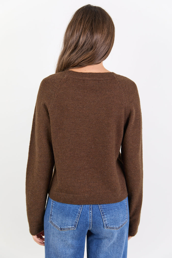 Person wearing a brown sweater and blue jeans on a white background