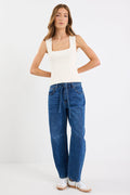 Woman wearing a white tank top and blue jeans on a white background