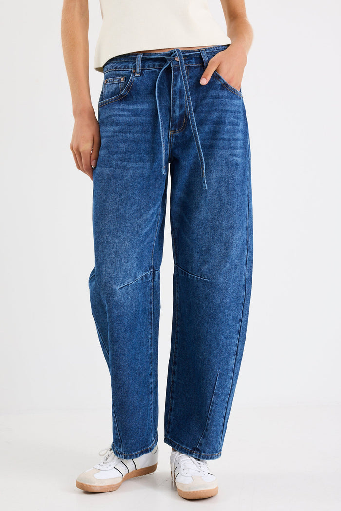 Person wearing blue jeans and white sneakers on a white background