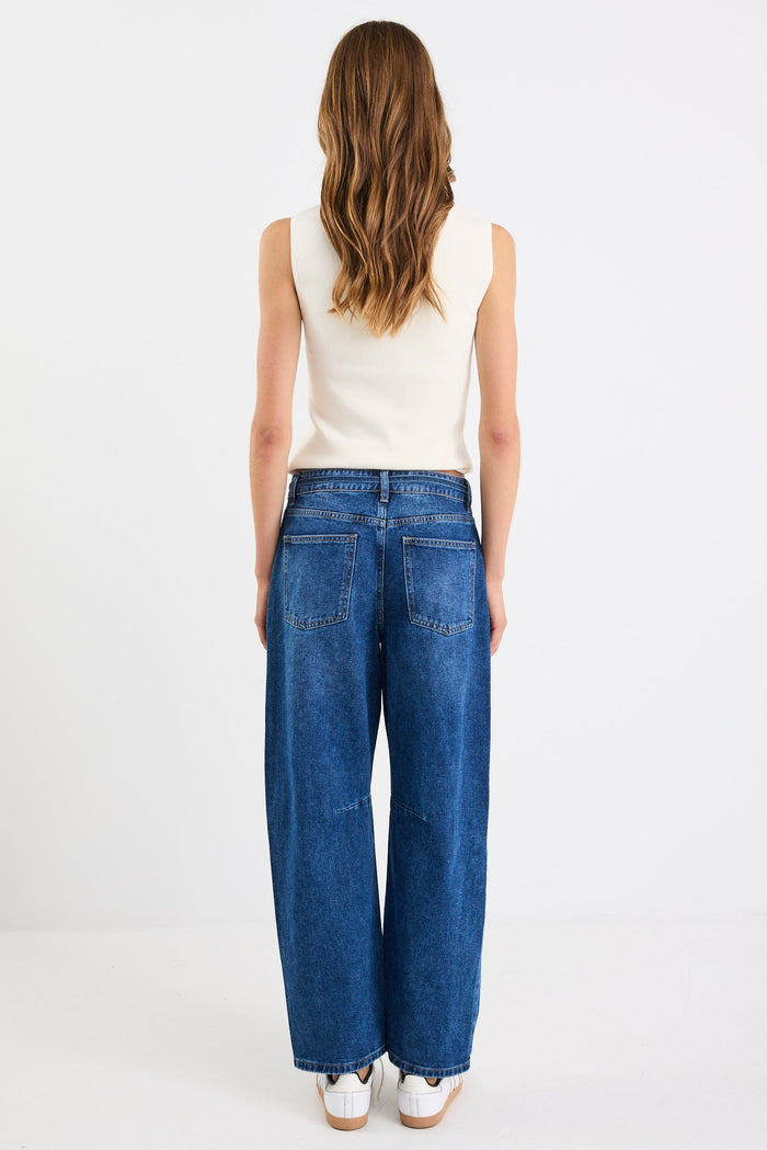 Person wearing blue jeans and a white top on a white background