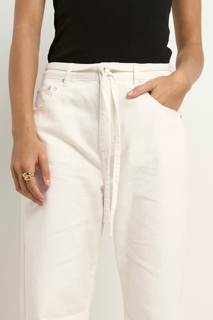 model wears a ecru barrel leg jeans with black tank top