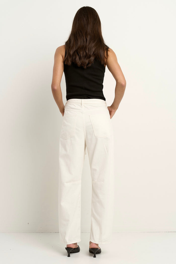 model wears a ecru barrel leg jeans with black tank top