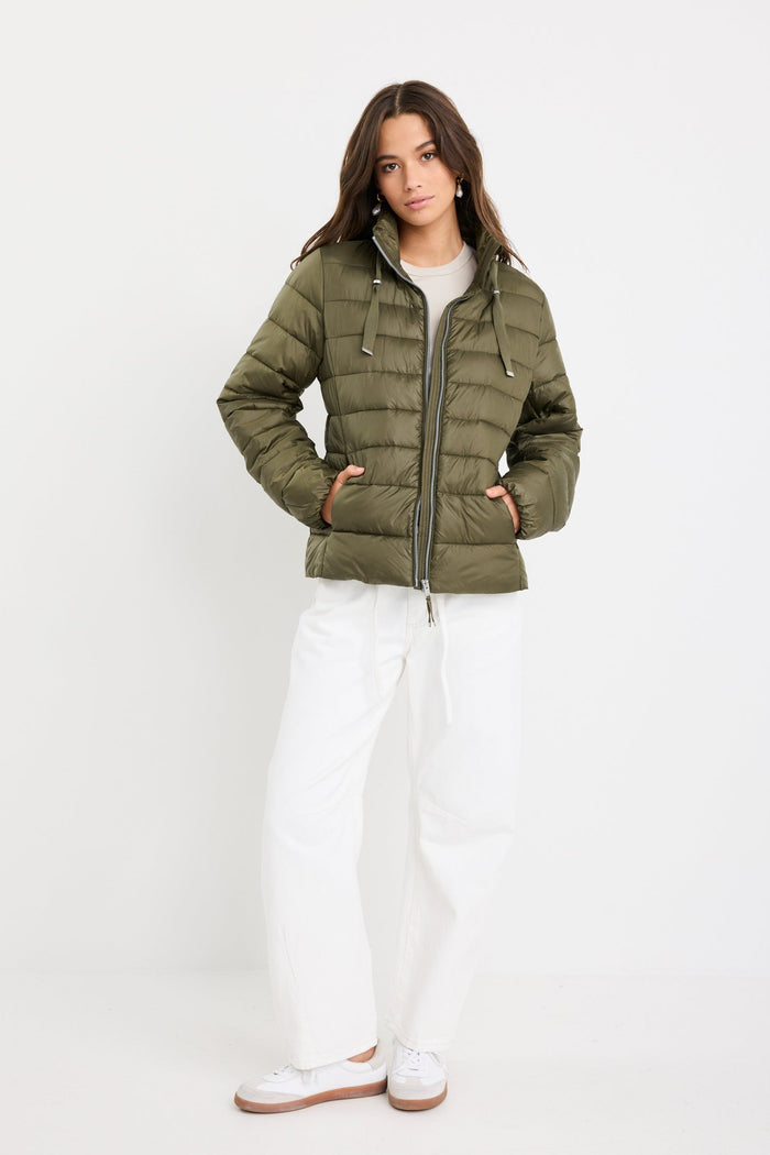 Woman wearing a green puffer jacket on a white background