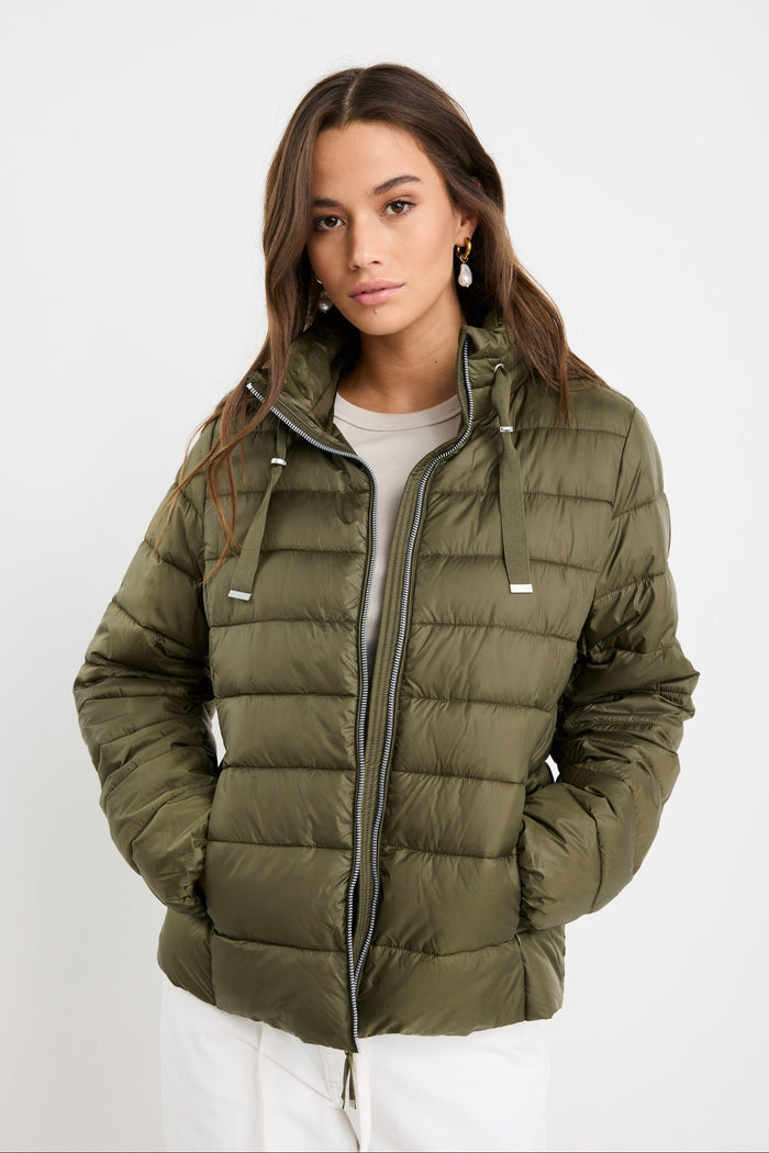 Woman wearing a green puffer jacket on a white background