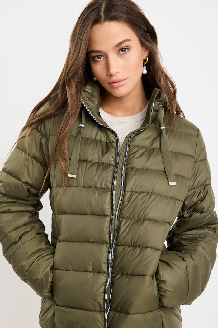 Woman wearing a green puffer jacket on a white background