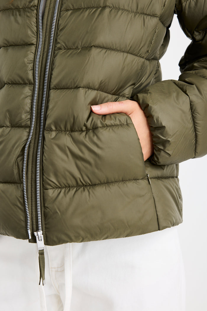 Close-up of a green puffer jacket with a hand in a pocket on a white background