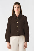 Woman wearing a brown jacket and beige pants on a white background