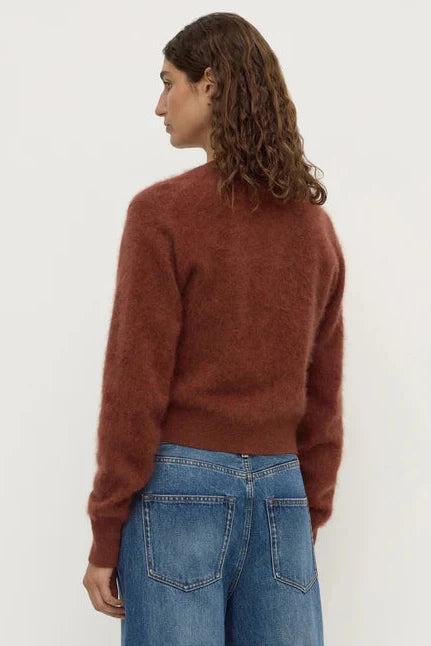 Person wearing a brown sweater and blue jeans on a white background