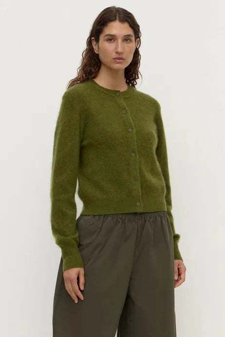 Woman wearing a green cardigan and brown pants on a white background