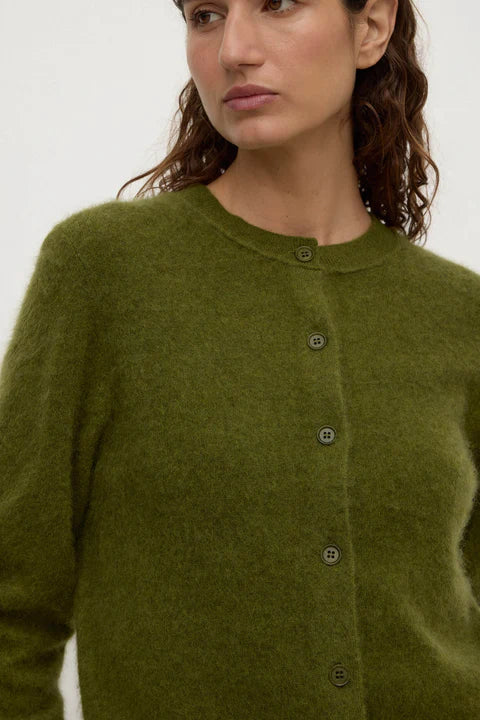 Woman wearing a green cardigan with a plain background