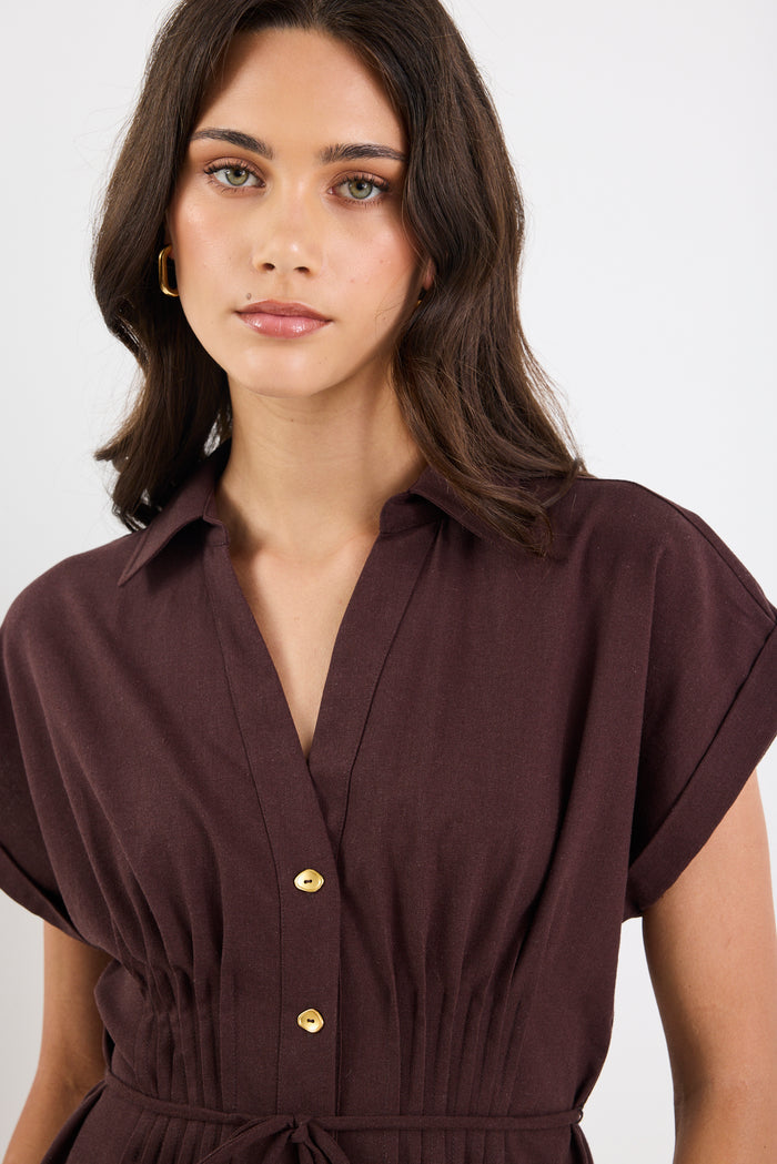Woman wearing a brown dress with gold buttons on a white background