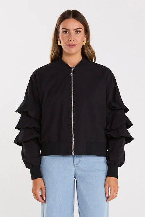 Person wearing a black bomber jacket and light blue jeans on a white background
