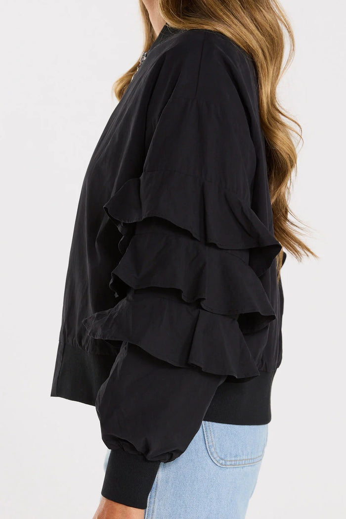 Black layered ruffle top worn by a person on a white background