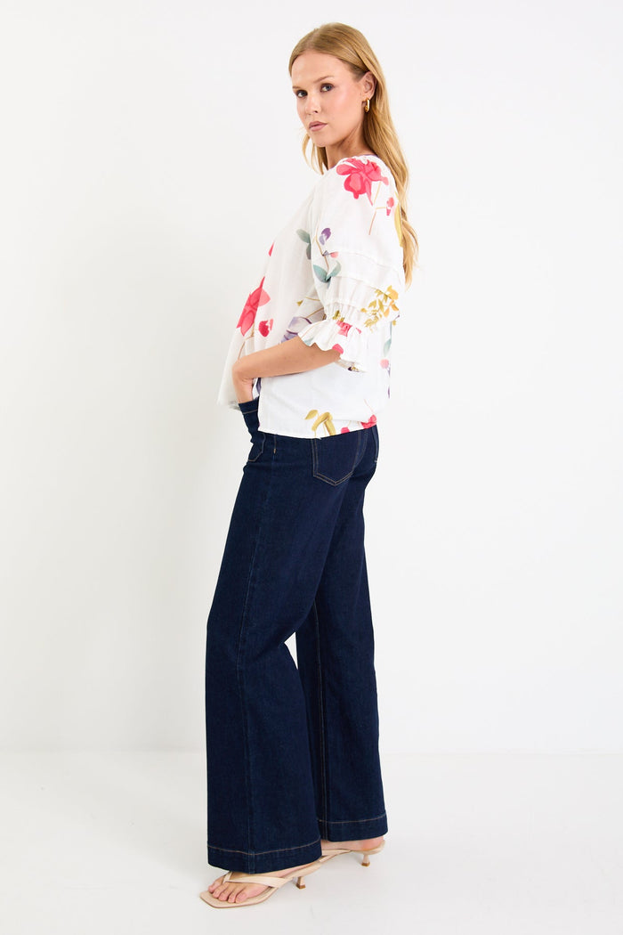 Woman wearing a cream floral poppy top and blue jeans