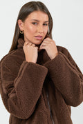 Woman wearing a chocolate brown sherpa fleece zip jacket and blue jean against a white background