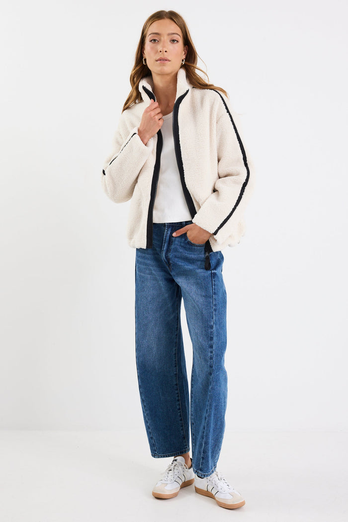 Person wearing a white jacket, white shirt, blue jeans, and white sneakers on a white background