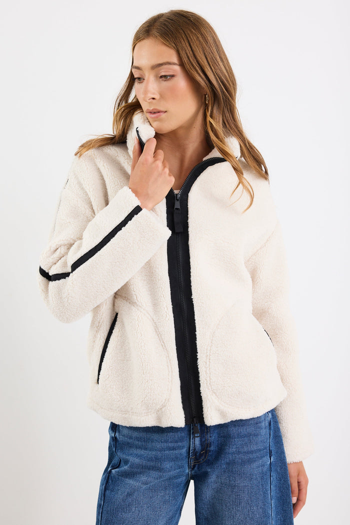 Woman wearing a white jacket with black trim on a white background