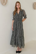 Woman wearing a charcoal animal print short sleeve dress with shirred bodice and tiered skirt, styled with black heels.