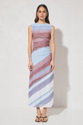 Woman wearing a sleeveless, long, multicolored dress against a white background