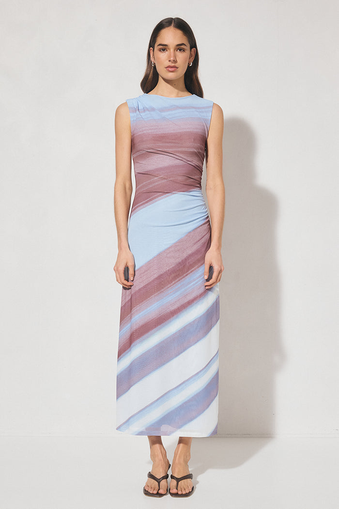Woman wearing a sleeveless, long, multicolored dress against a white background