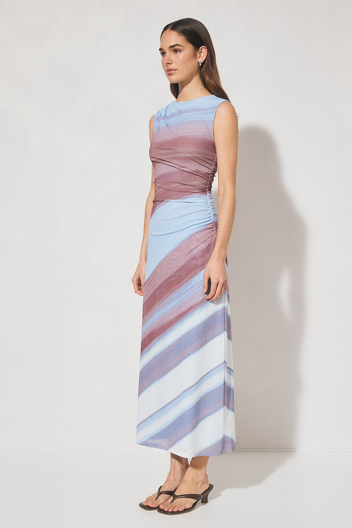 Woman wearing a sleeveless, striped dress with a gradient of colors against a plain background
