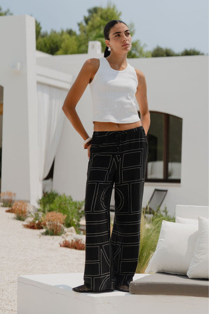 model wears a black wide leg pant with a white tank top