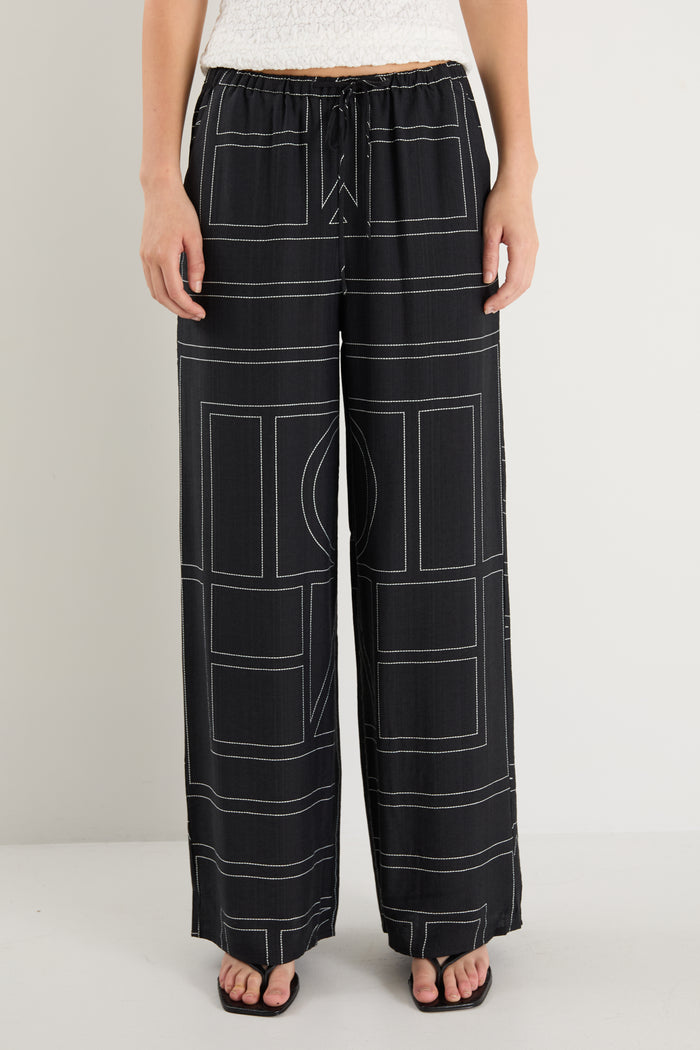 model wears a black wide leg pant with a white tank top