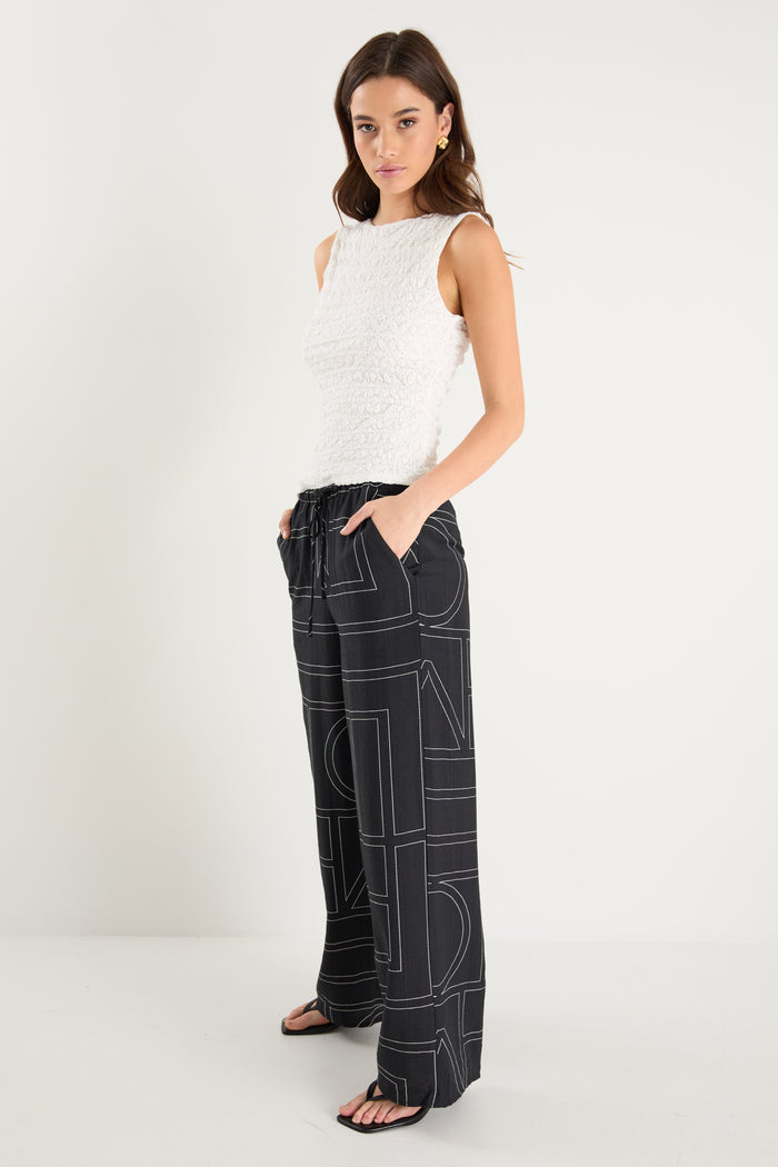 model wears a black wide leg pant with a white tank top