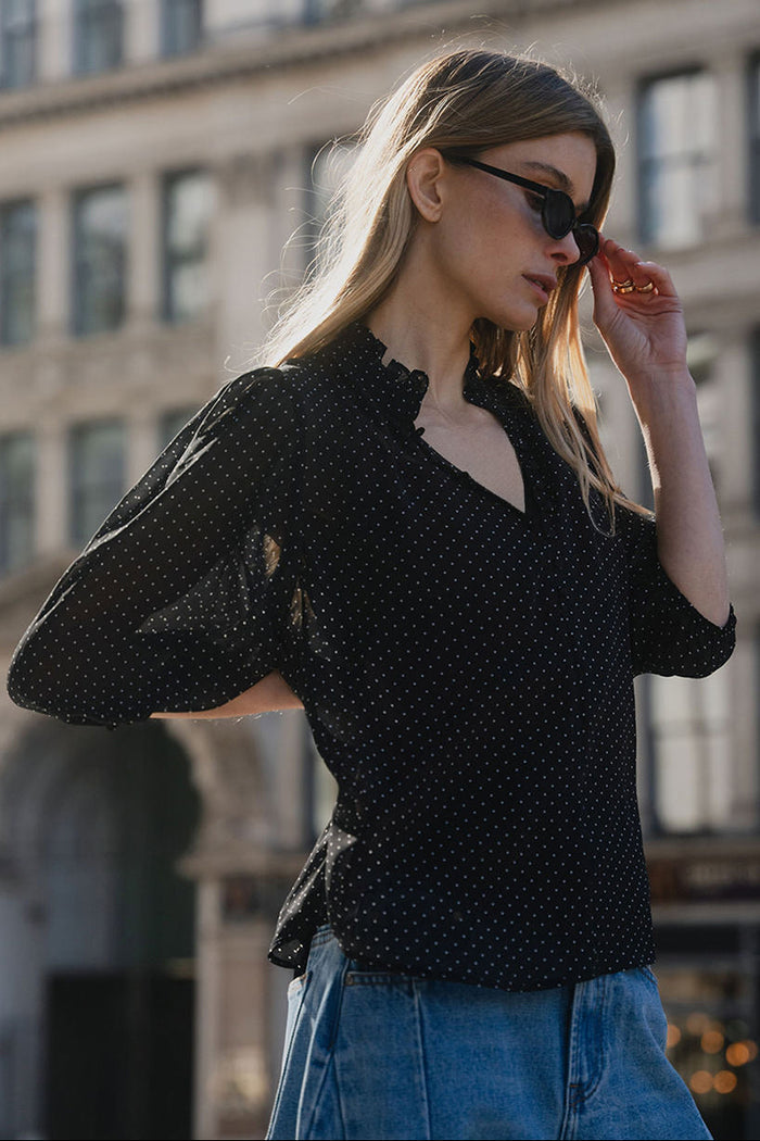 Woman wearing a black polka dot blouse and blue jeans in an urban setting