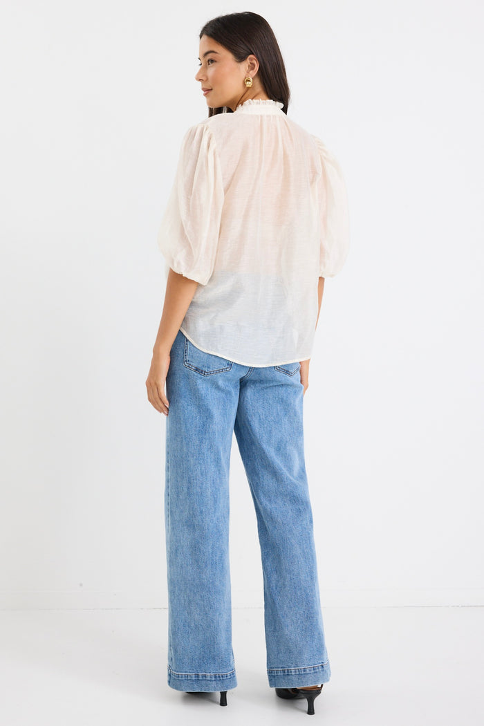 model wears a white blouse with light blue high waisted jeans
