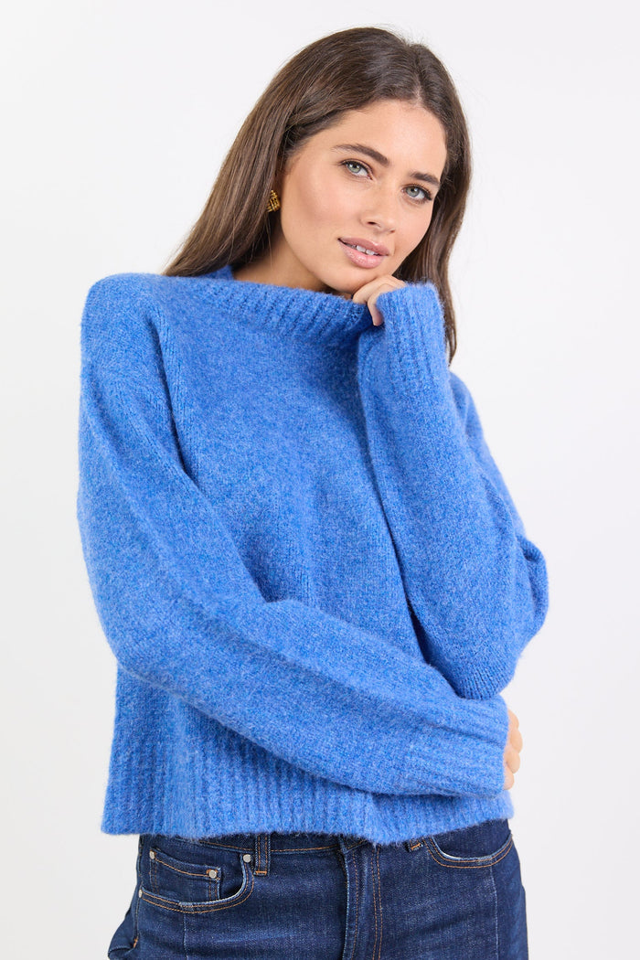 Woman wearing a blue sweater and jeans on a white background