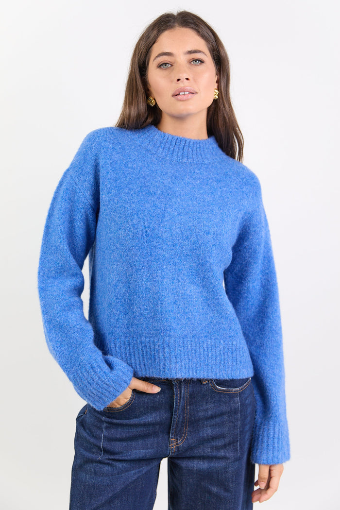 Woman wearing a blue sweater and jeans on a white background