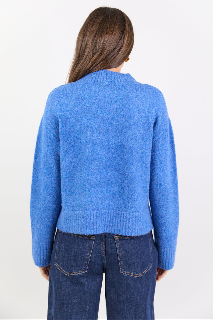 Person wearing a blue sweater and jeans on a white background