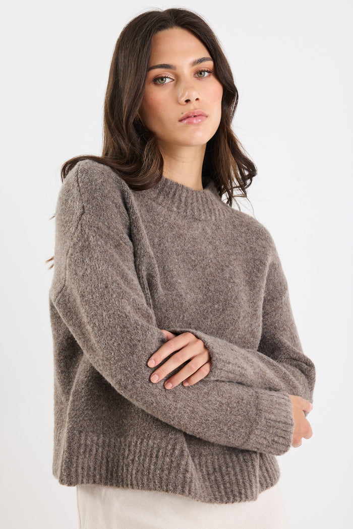 Woman wearing a gray sweater against a white background