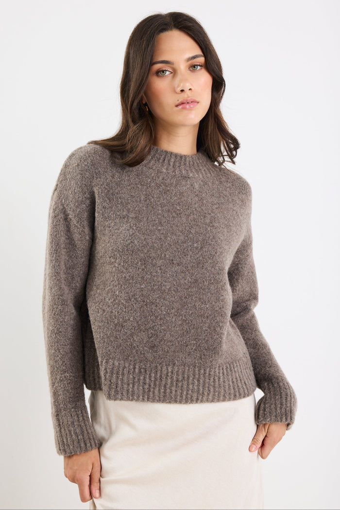 Woman wearing a brown sweater against a white background