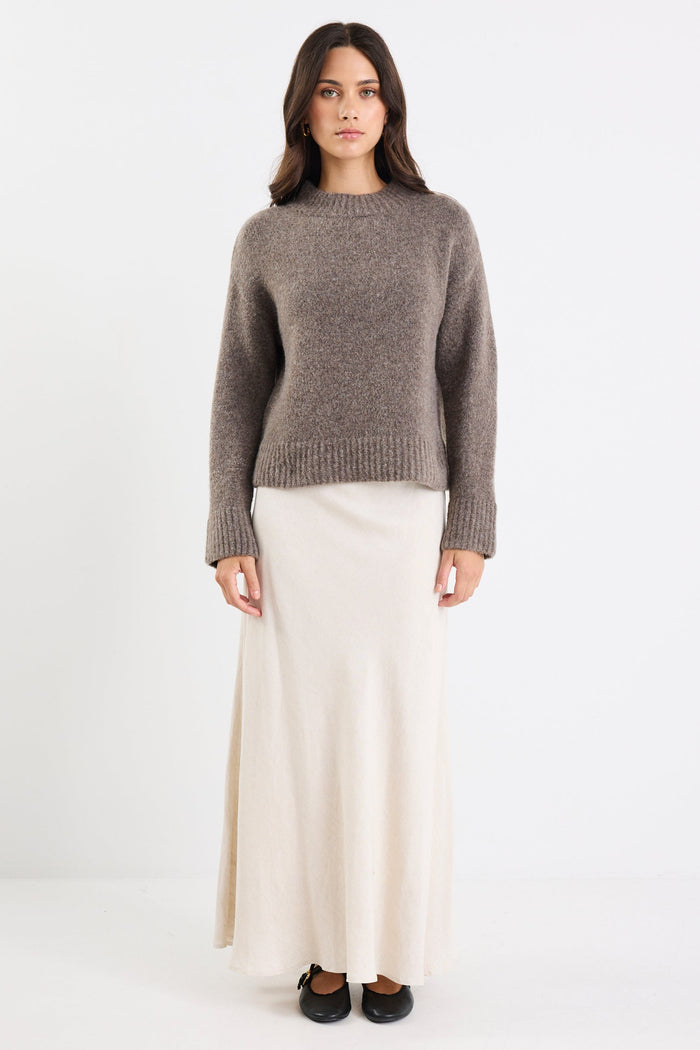 Woman wearing a gray sweater and white skirt on a white background