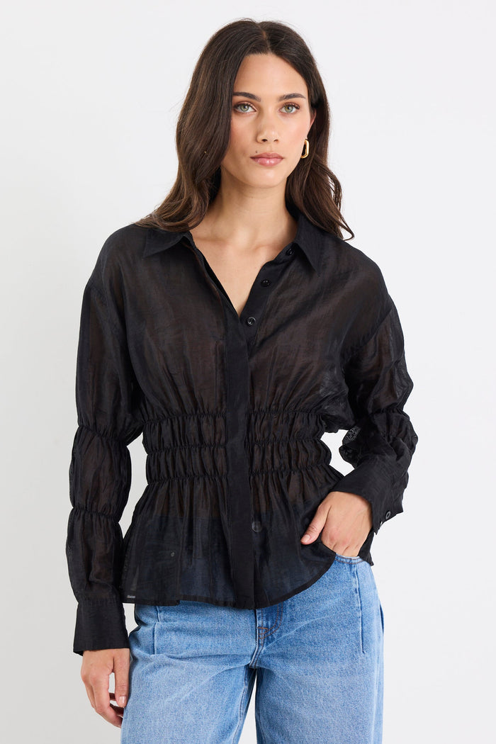 Woman wearing a black blouse and blue jeans on a white background