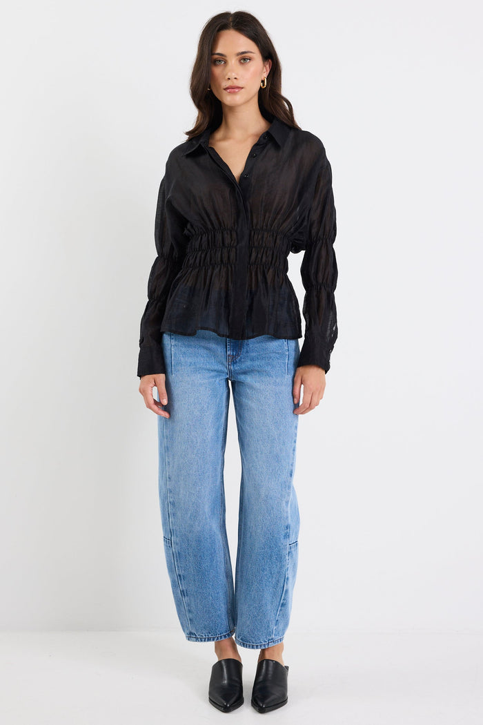 Woman wearing a black blouse and blue jeans on a white background
