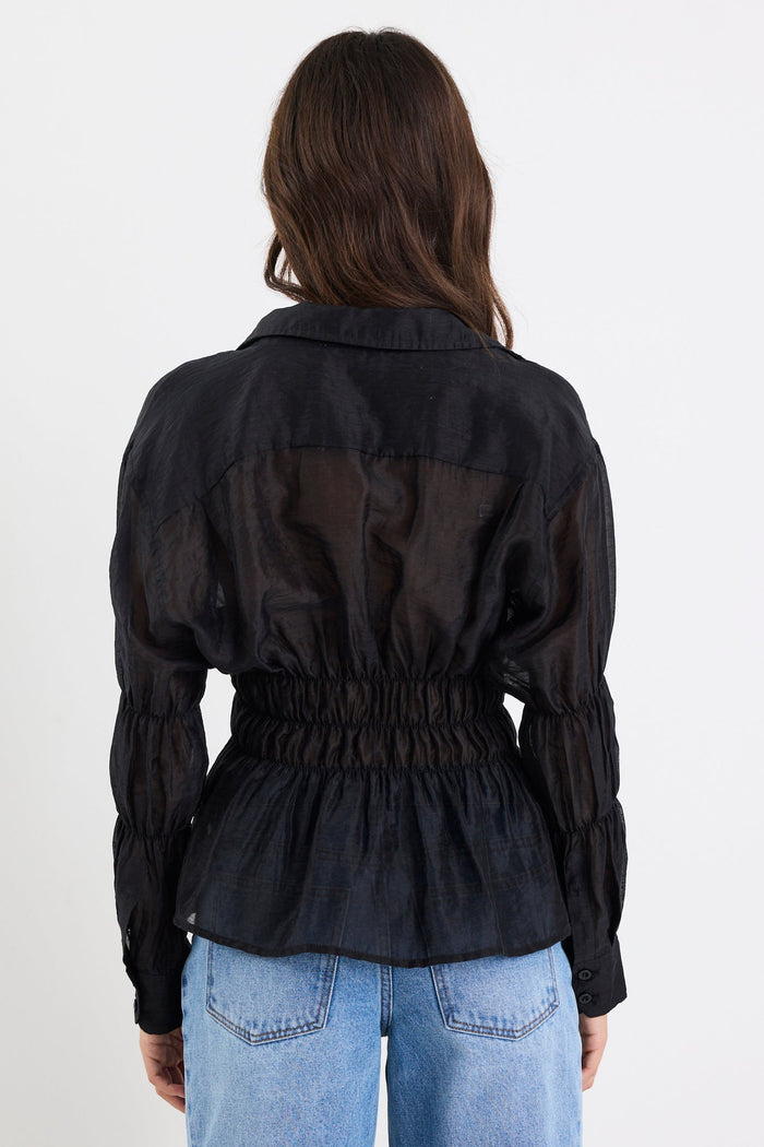 Person wearing a black jacket and blue jeans on a white background